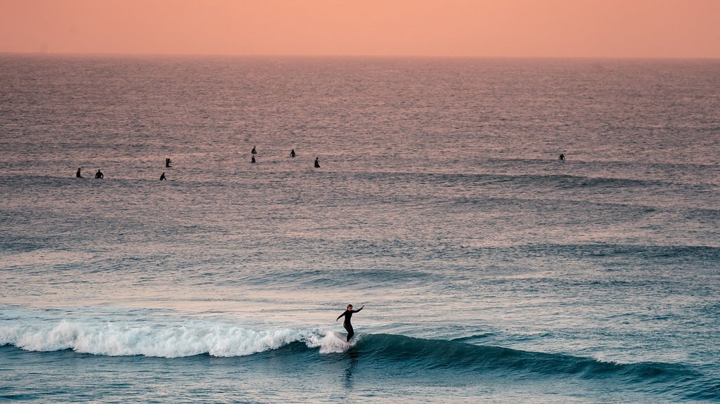 Eine Surferin surft im Weißwasser bei Sonnenuntergang