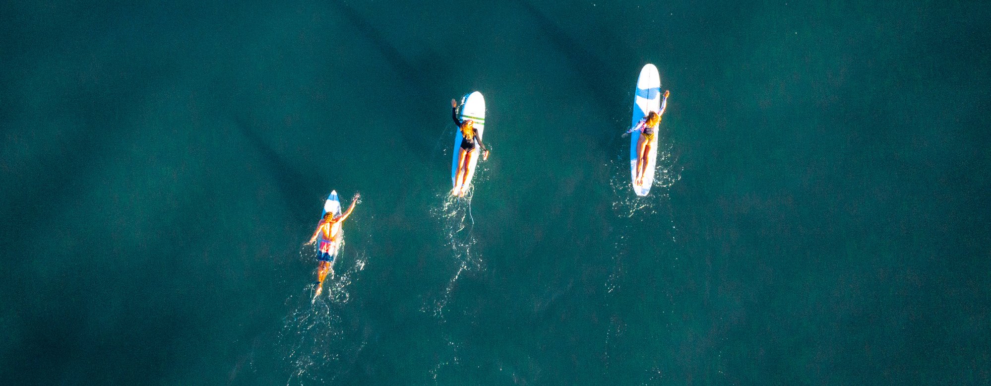 Wellenreiten: Drohnenfoto von der Atlantikküste mit drei Longboardern