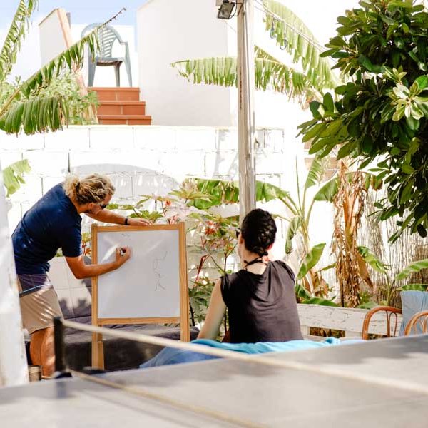 Surflehrer erklärt Schülerin im gemütlichen Innenhof die Surftheorie