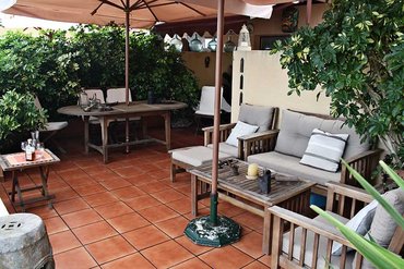 Gemütlicher Innenhof mit Sitzgelegenheiten, Schirmen, Pflanzen und roten Kacheln