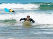 Ein Junge paddelt auf seinem Surfbrett durchs Weisswasser