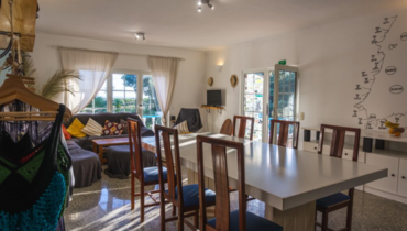 Gemütliches Wohnzimmer im Surfhaus mit Esstisch, Couch und kleinem Shop