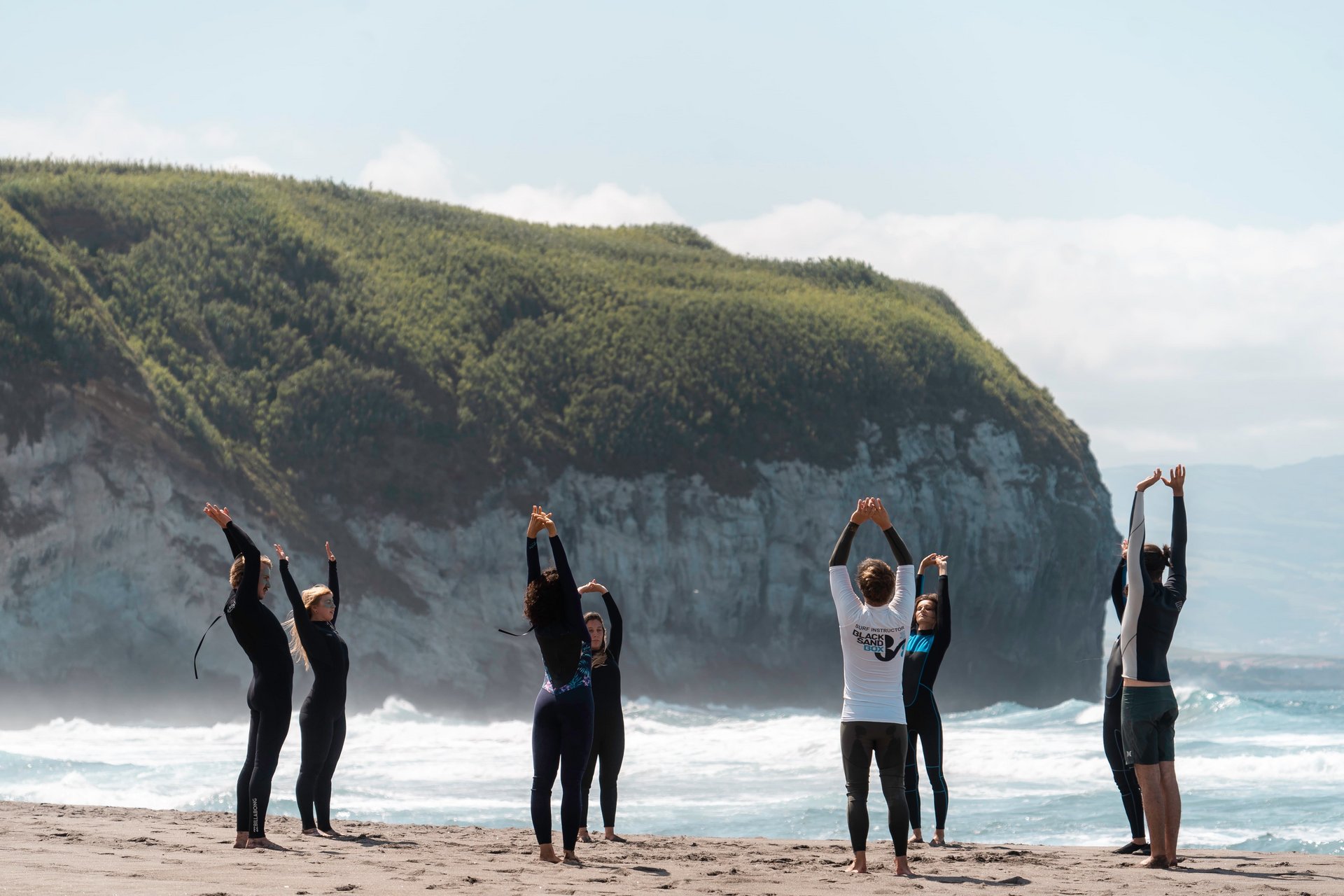 Eine Gruppe Surfer macht Dehnübungen am Strand