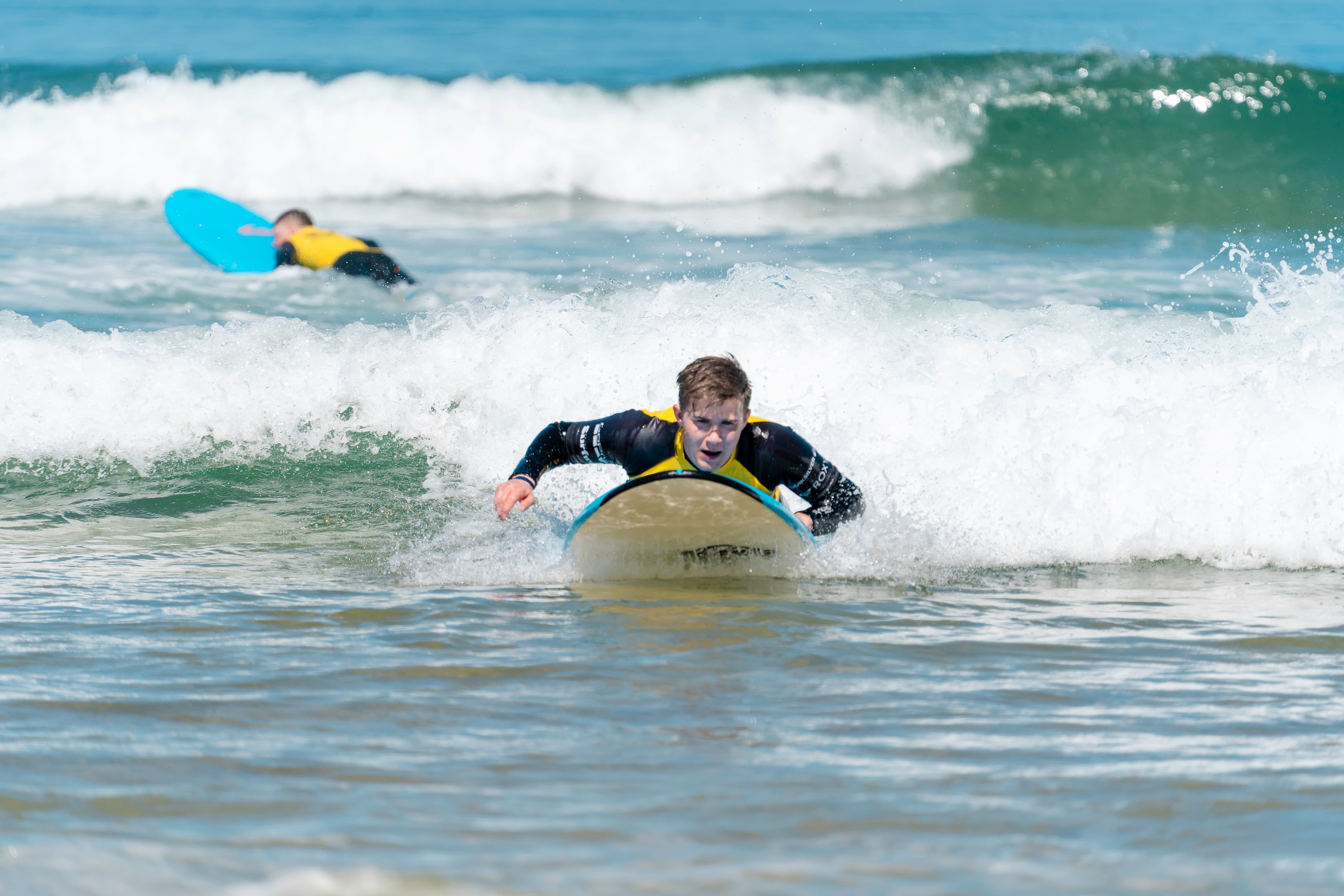Ein Junge paddelt auf seinem Surfbrett durchs Weisswasser